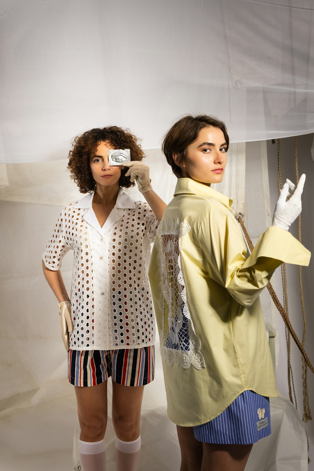 two-women-holding-condom-packets-one-covering-eye-qpmxycoiss8